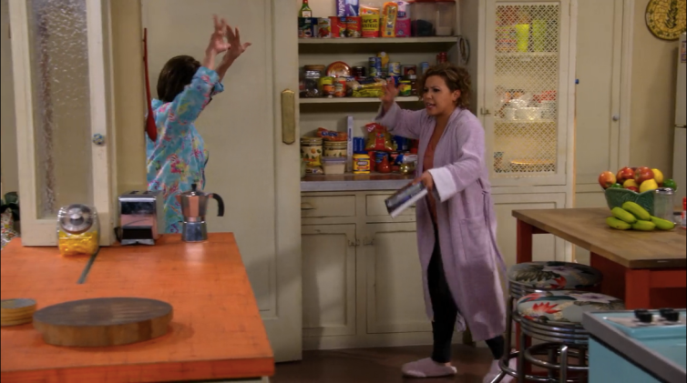 Rita Moreno dances in pajamas and Justina Machado follows in slippers and bathrobe in the kitchen set for Netflix series "One Day at a Time"