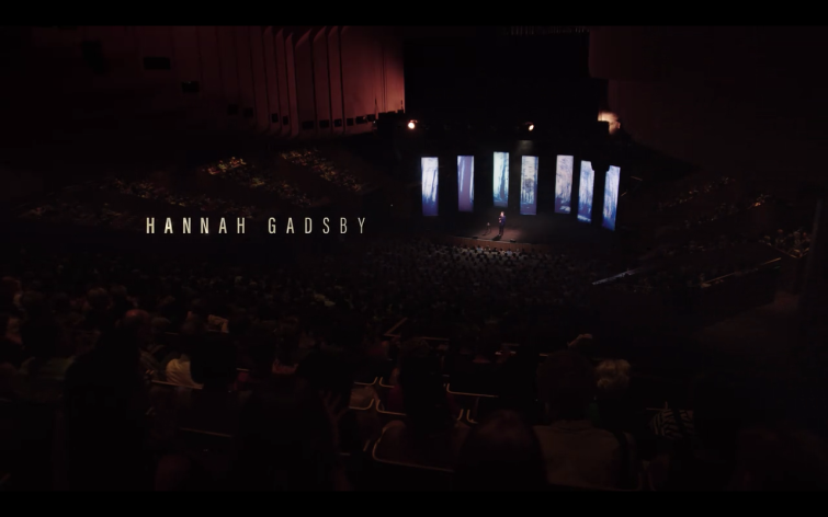 Text reads "Hannah Gadsby" over a wide shot of the auditorium