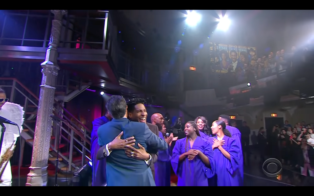 Stephen Colbert and Jon Stewart hug in front of a gospel choir and live studio audience on The Late Show June 14, 2021