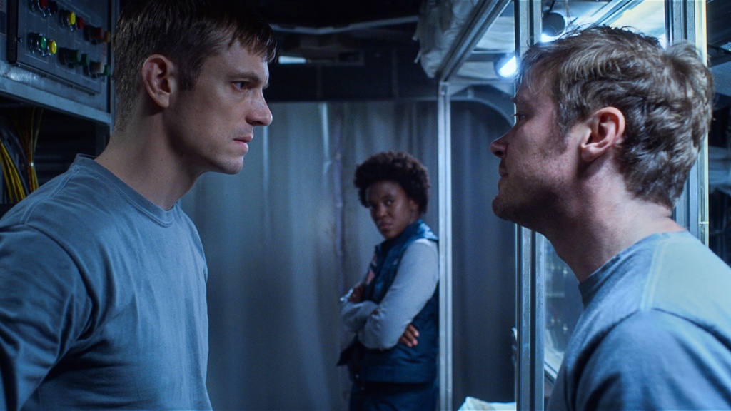 Joel Kinnaman and Michael Dorman confront each other in foreground as Krys Marshall looks on in the background. Ed Baldwin, Danielle Poole and Gordo Stevens are aboard the Jamestown Moon Base in "For All Mankind" season 1.